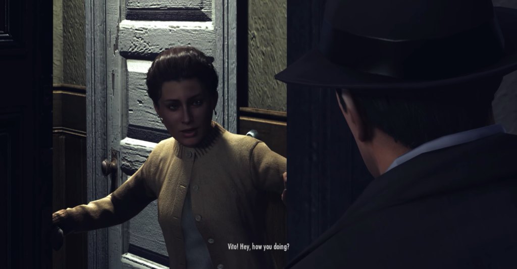 Woman in cardigan greets man at door.