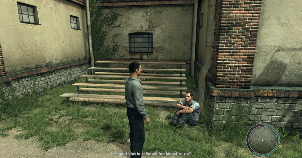 Two men converse near wooden benches.