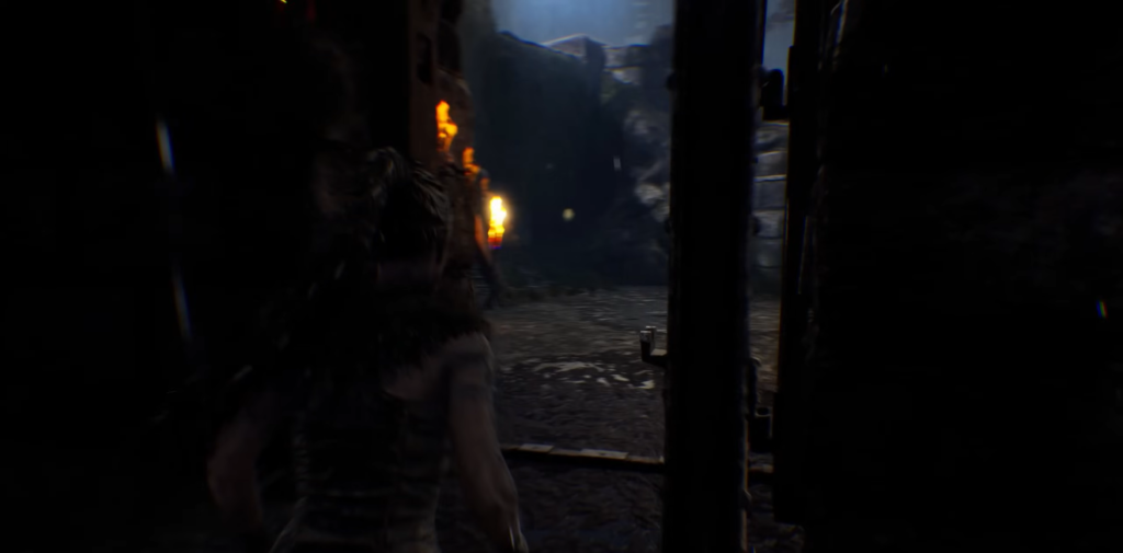 Woman walking through dark corridor with firelight