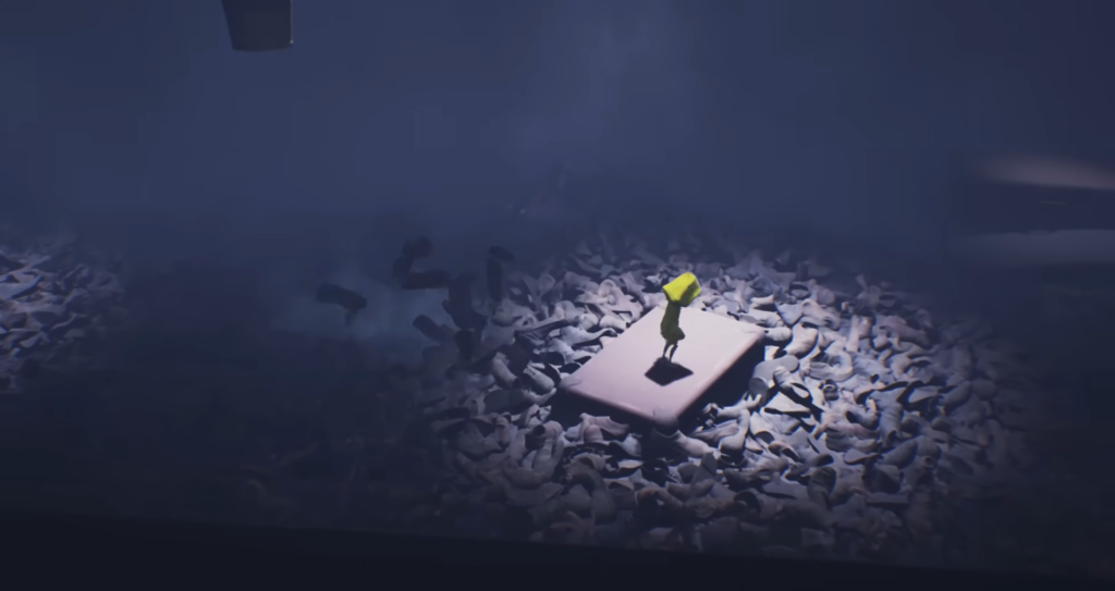 Six from Little Nightmares stands on mattress in shoes