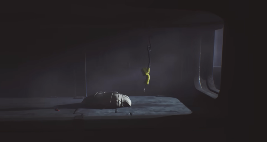 Yellow raincoat figure hangs from hook in dark room