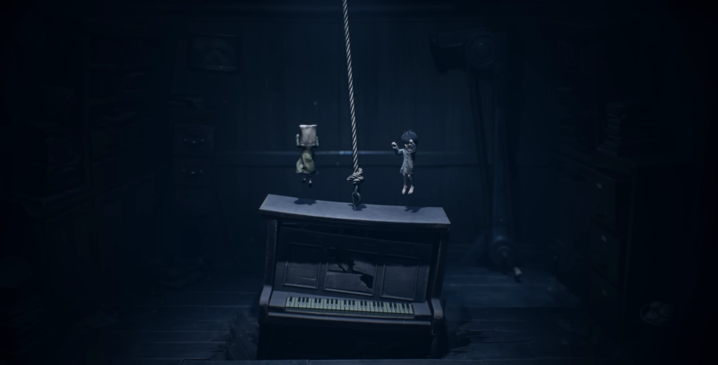 Two children jump on piano in dark room