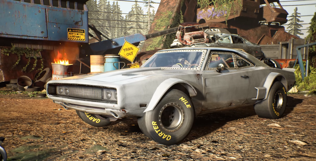 Gray muscle car parked in scrapyard with fire