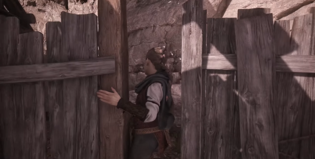 Amicia opening wooden gate in rocky setting.