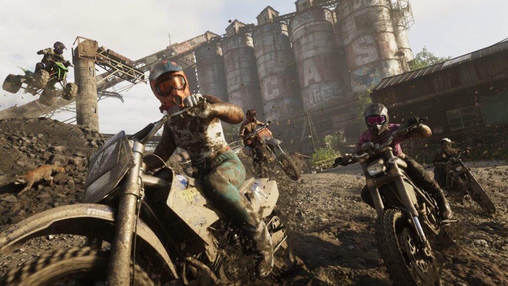 Dirt bike riders racing through industrial yard with silos
